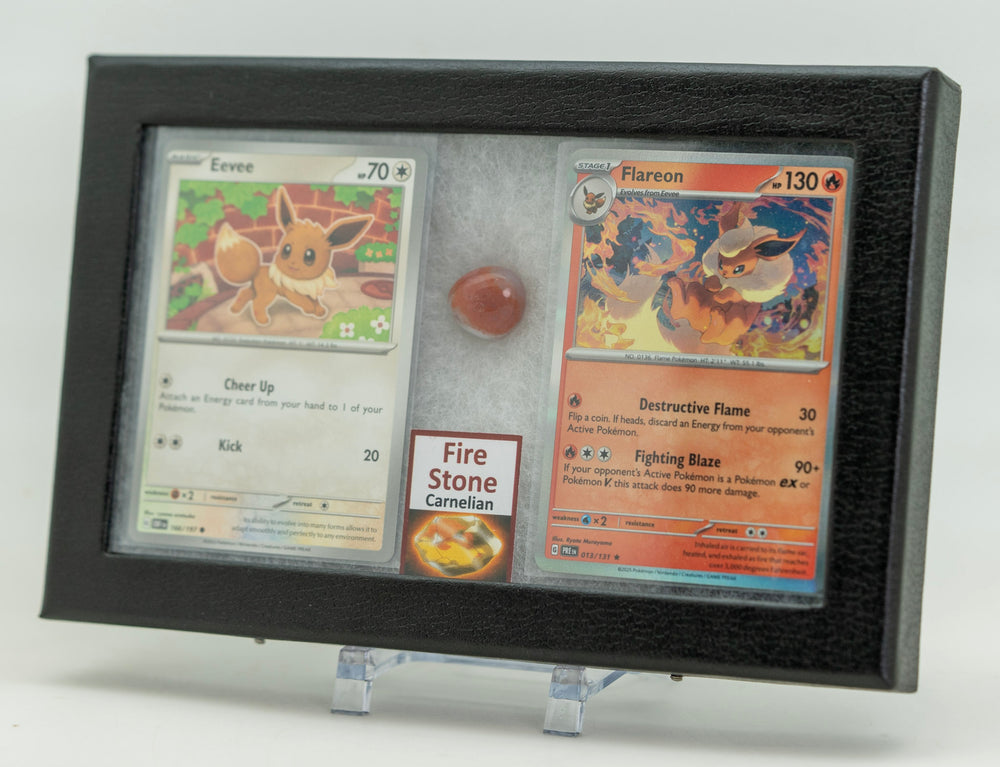 Two trading cards displayed in a black frame with a small gemstone on a white background