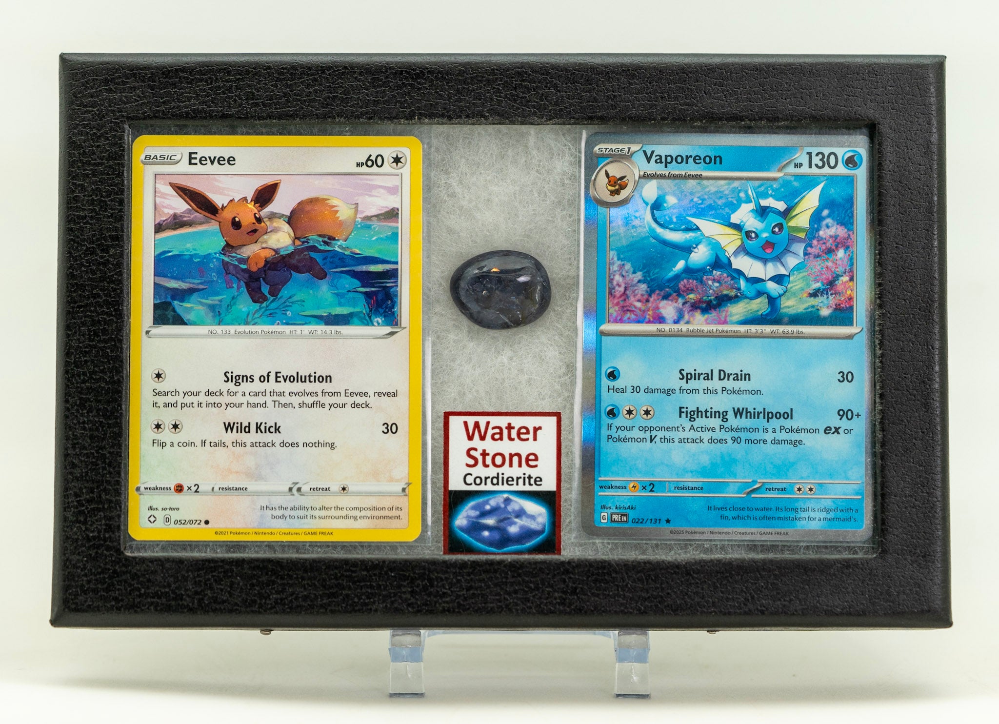 Two trading cards displayed in a frame with a stone underneath